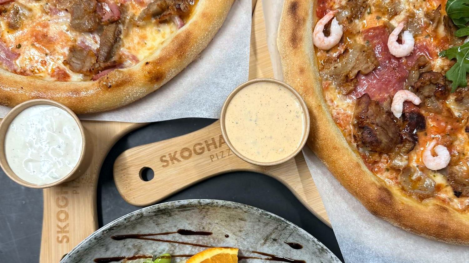 Två pizzor på Skoghalls pizzabrädor, dippsåser och en sallad med chèvre och lufttorkad skinka