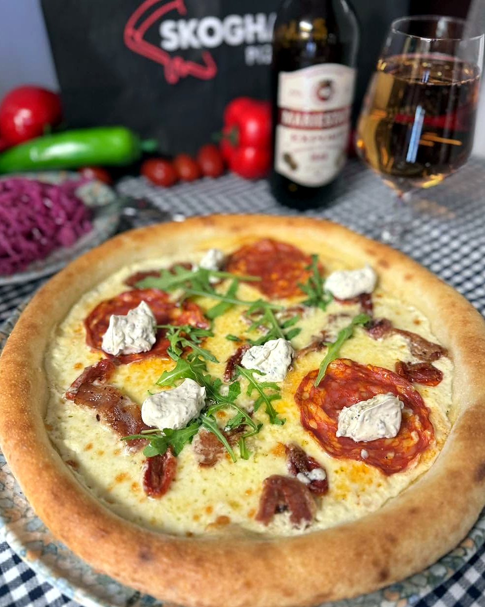 Pizza på crème fraiche-botten med salami, bacon, örtkräm och ruccola, Skoghalls-påsen i bakgrunden